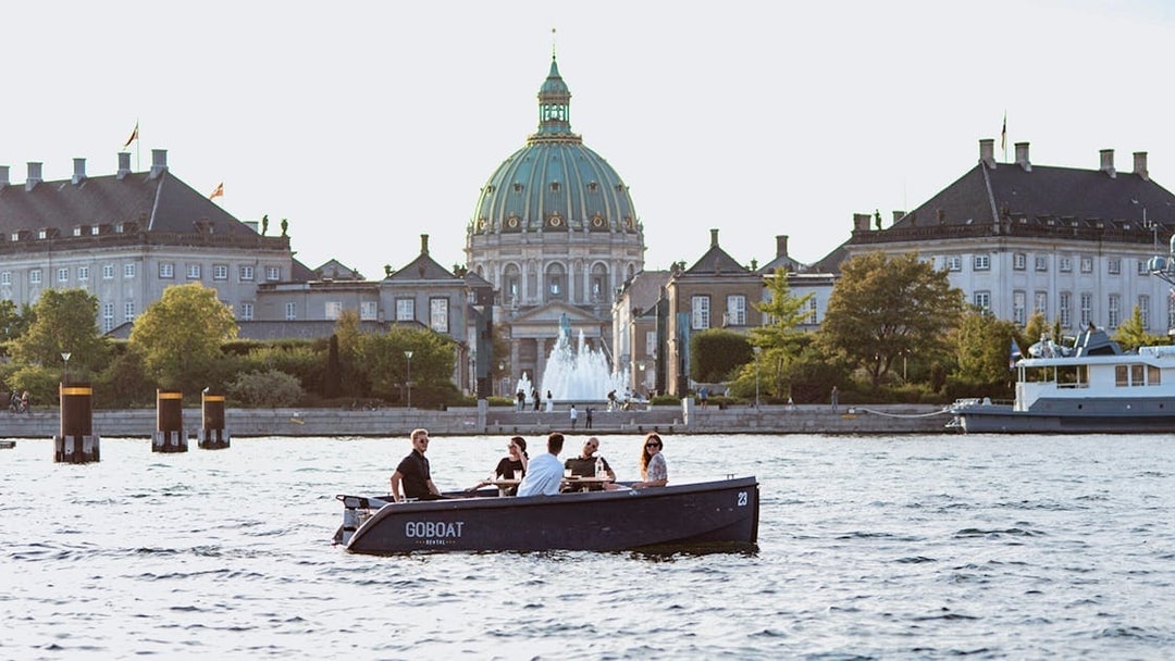 Guests on a boat tour in Copenhagen with Fredrick's Church in the background.