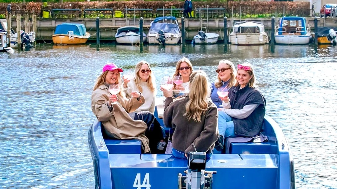 Guests enjoying a boat tour in Copenhagen harbor with colorful waterfront buildings.