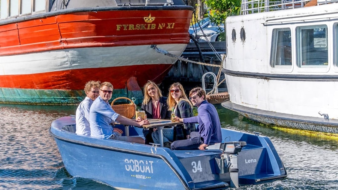 Guests enjoying a boat tour in Copenhagen harbor, passing by historic ships.
