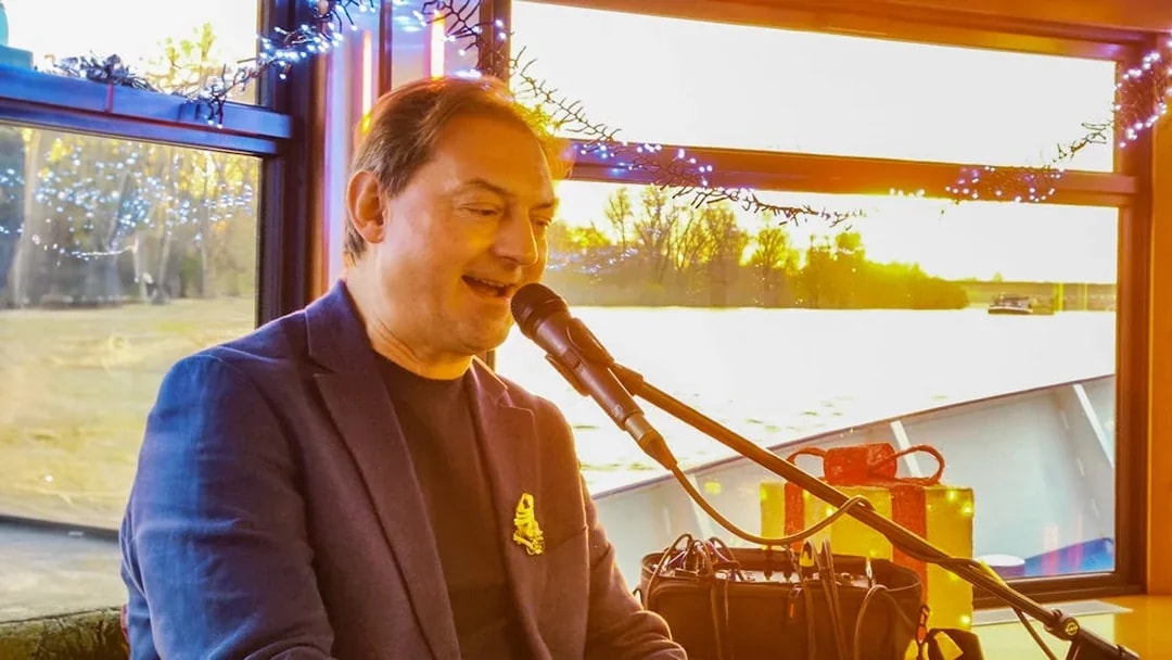 Musician performing on a boat during Cologne Advent tour with festive decorations.