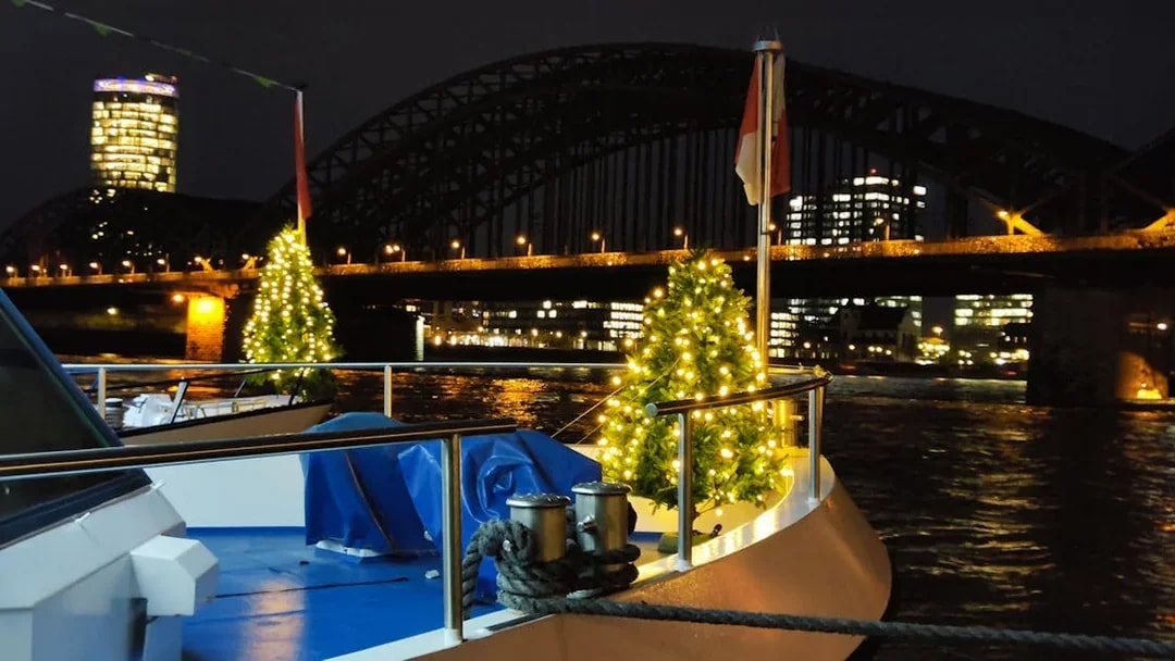 Boat with Christmas lights on the Rhine River, Cologne, near Hohenzollern Bridge at night.