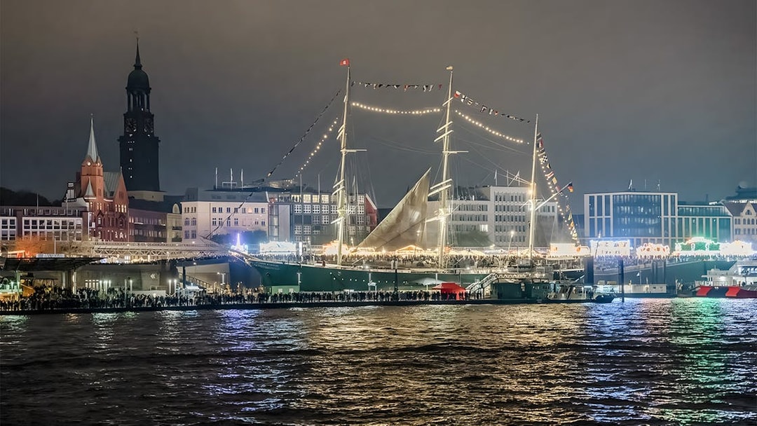 Grand Harbor illuminated at night with a tall ship and city skyline during evening lights cruise.