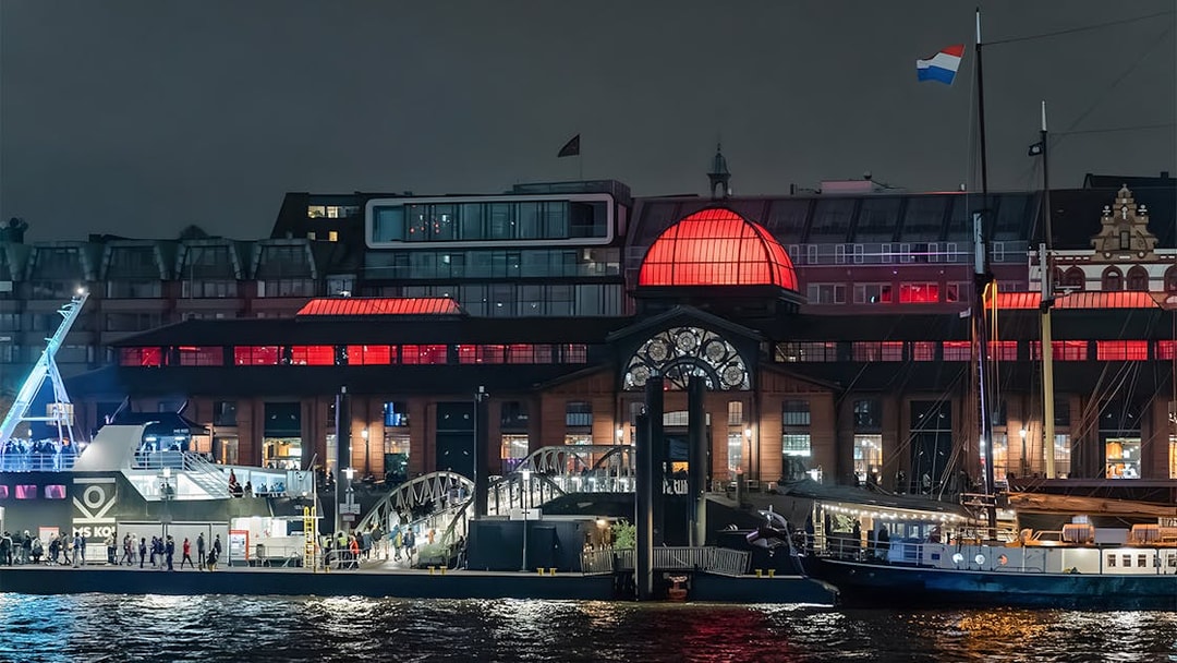 Grand Harbor evening cruise with illuminated waterfront building and docked ship.