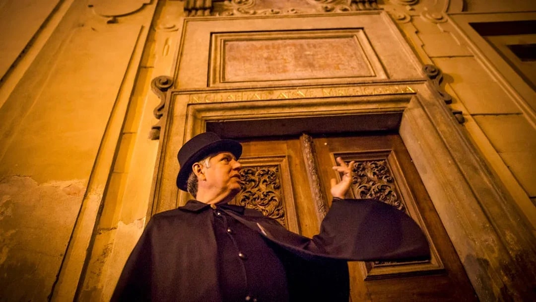 Guide in cloak gestures during Prague Old Town ghost tour.