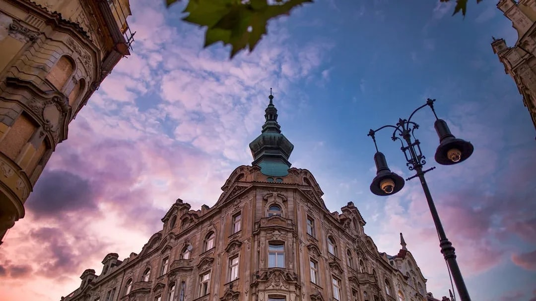 Historic building and street lamp at sunset in Prague's Old Town.