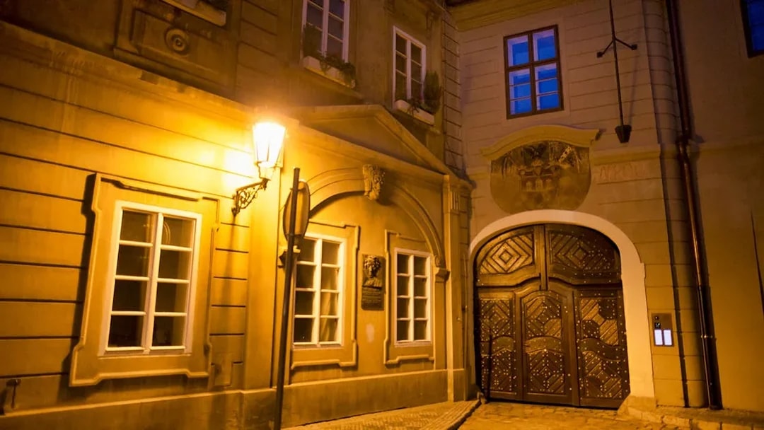 Historic Prague street at night with illuminated old town architecture.