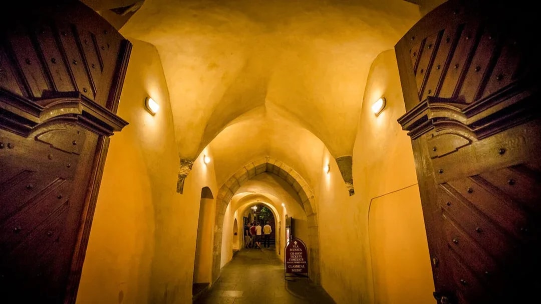 Dimly lit arched hallway in Prague's Old Town, part of the evening ghost tour.