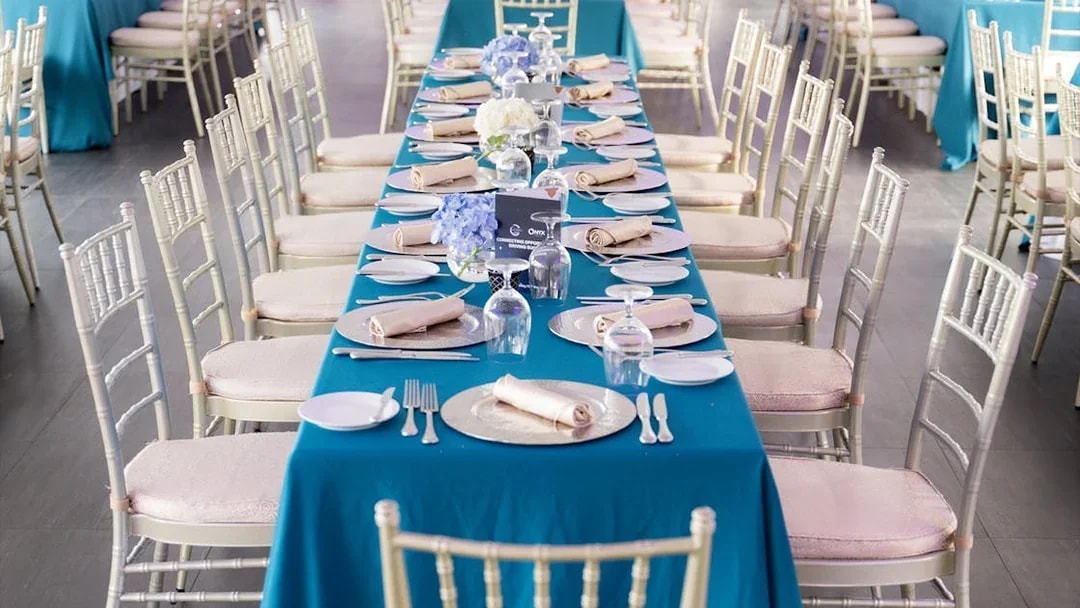 Elegant dining setup on Meridian Dinner Cruise with blue tablecloths and floral centerpieces.