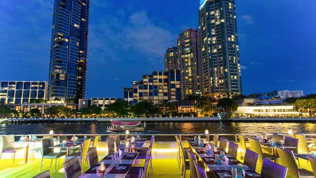 Dinner tables set on a cruise ship with city skyline view at IconSiam Pier No.4, Bangkok.