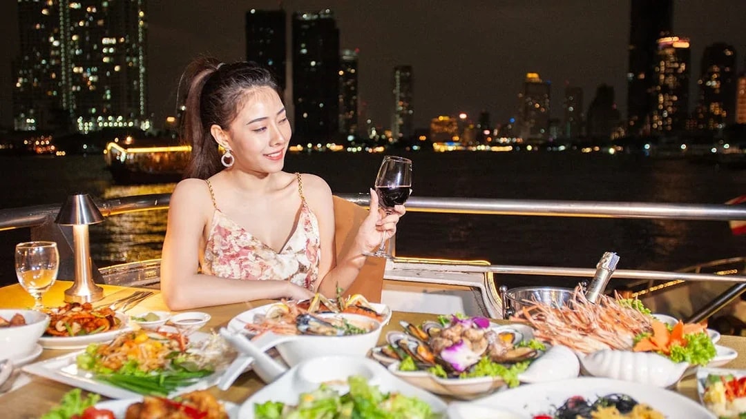 Buffet dinner on Chao Phraya Cruise with city skyline in Bangkok.