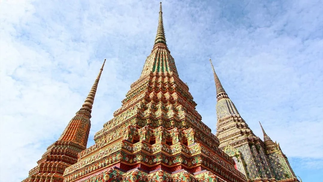 Colorful spires of Wat Pho temple in Bangkok under a clear sky.
