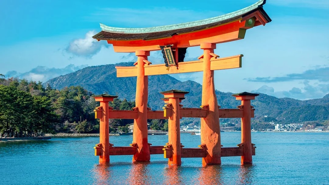 Torii gate at Itsukushima Shrine, Miyajima, with mountains in the background.