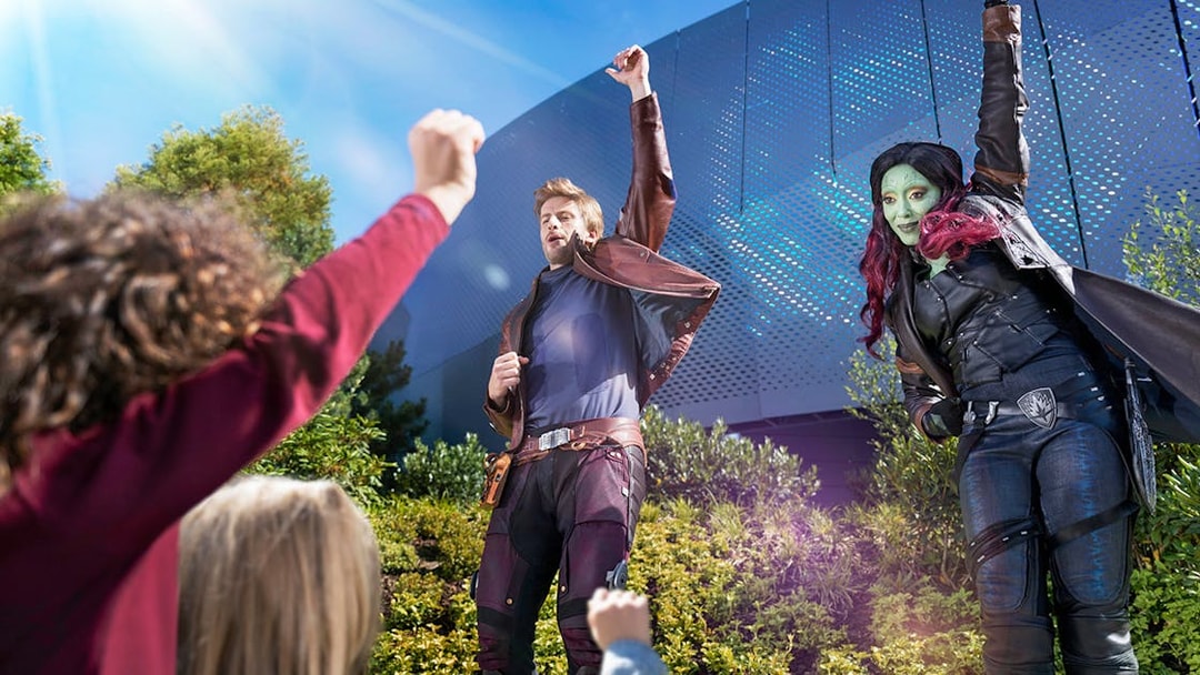 Characters in costume interacting with children at a theme park attraction.