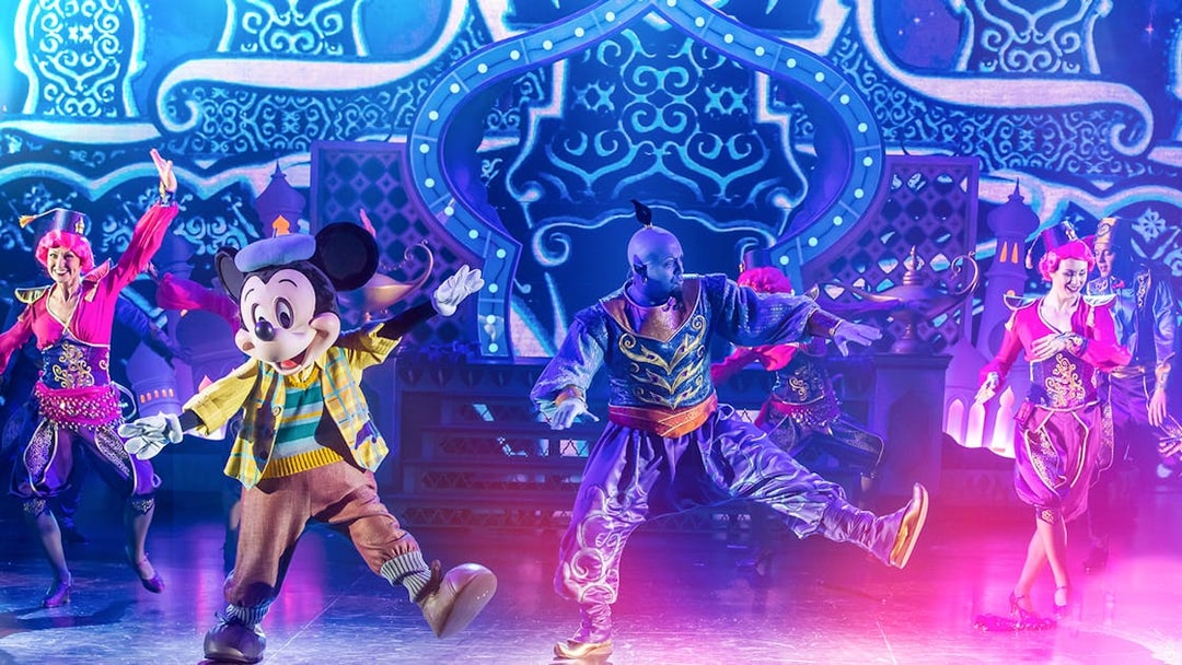 Characters performing a vibrant stage show with colorful costumes and an ornate backdrop.