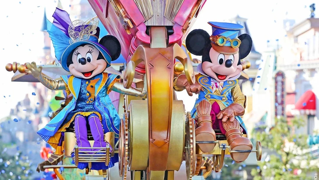 Mickey and Minnie Mouse in colorful costumes on a parade float at Disneyland Paris.
