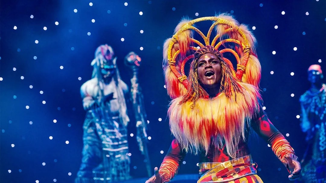 Performer in vibrant costume on stage during a show at Disneyland® Paris.