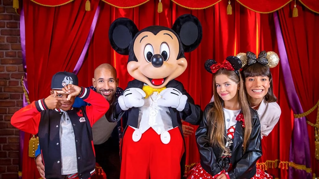 Family posing with Mickey Mouse at Disneyland® Paris.
