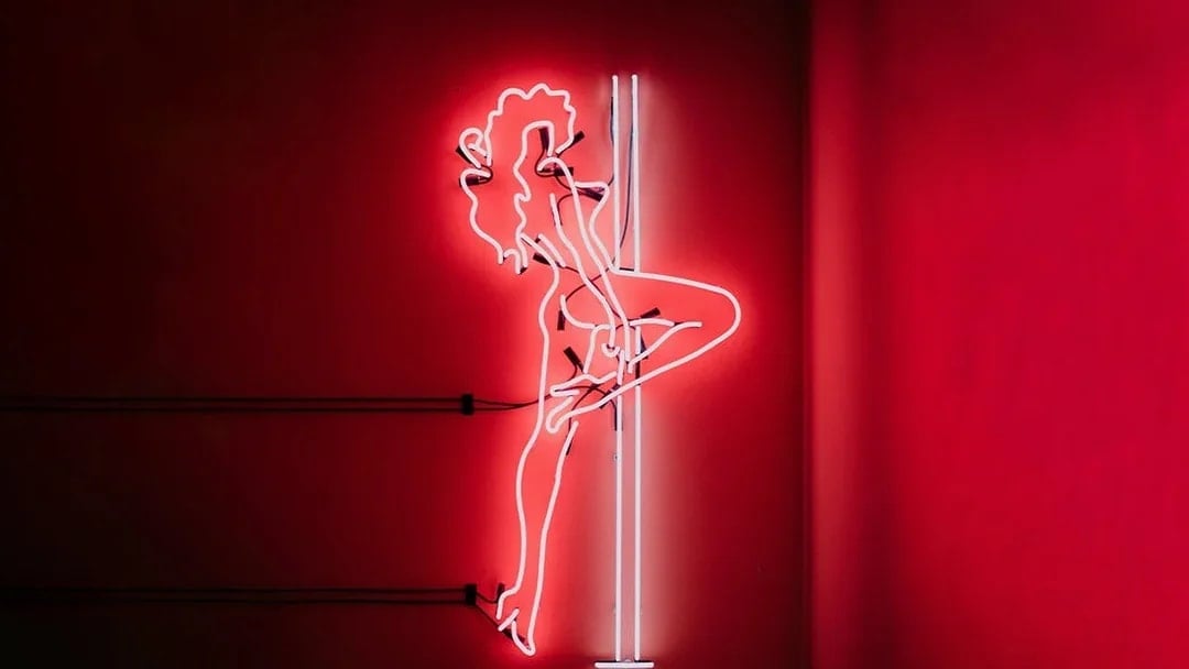 Neon silhouette of a dancer on a pole, part of the Tour de BonTon experience.