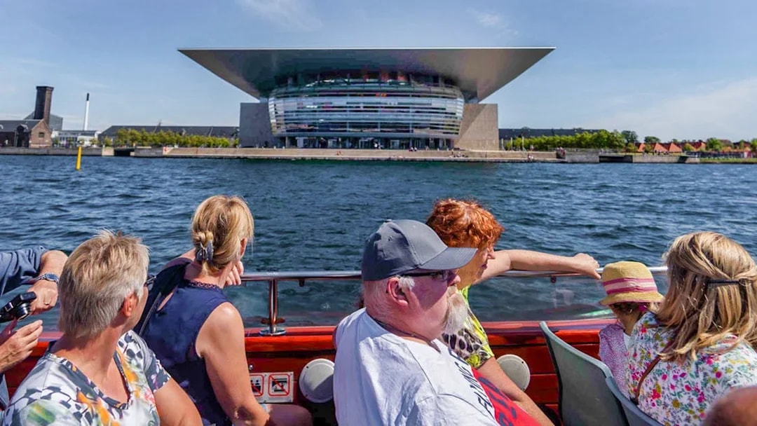 Cruise passengers view Copenhagen Opera House from the water.