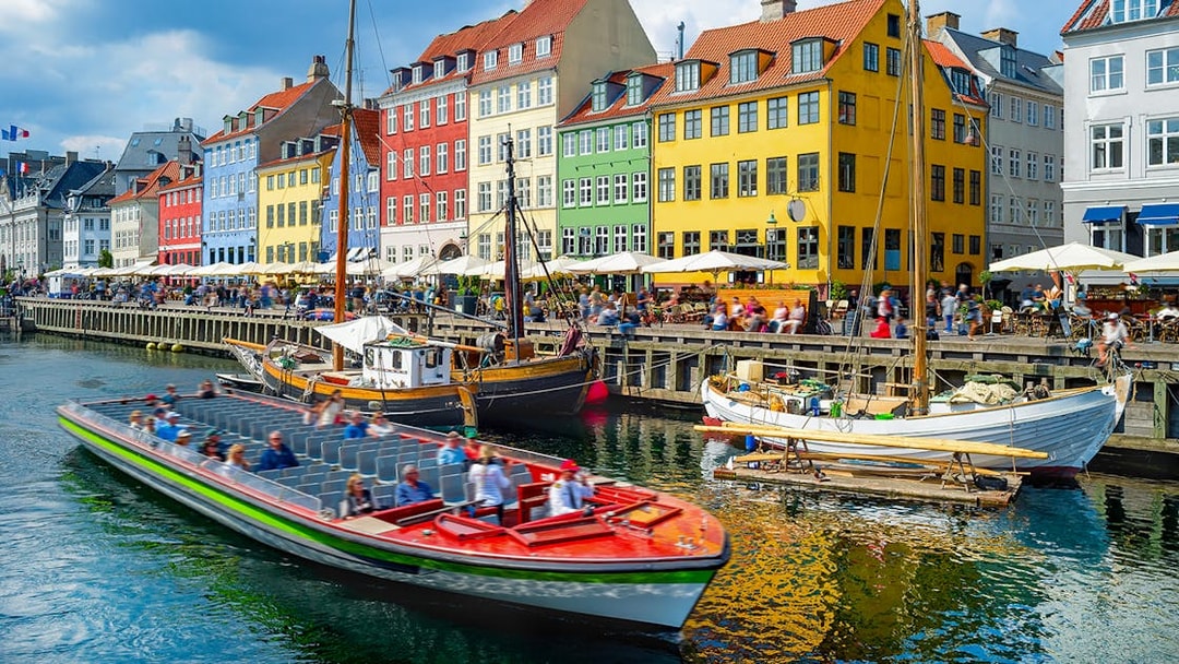 Tour boat cruising by colorful buildings in Nyhavn, Copenhagen.