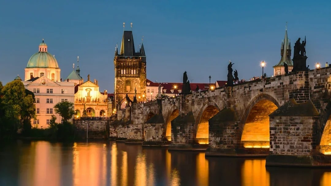 Charles Bridge and Prague skyline at dusk during sightseeing cruise.