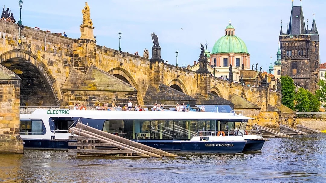 Cruise boat on Vltava River near Charles Bridge in Prague.