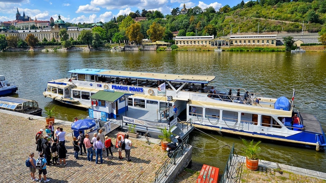 Vltava River cruise boat docked in Prague with tourists boarding.