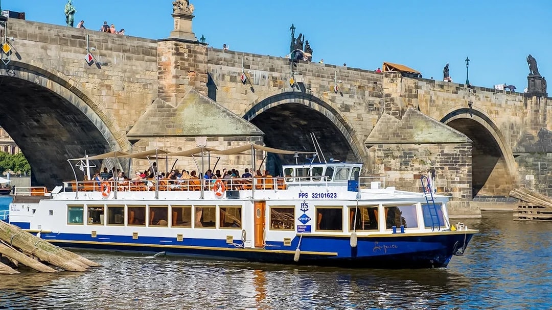 Sightseeing boat on Vltava River near Charles Bridge in Prague.