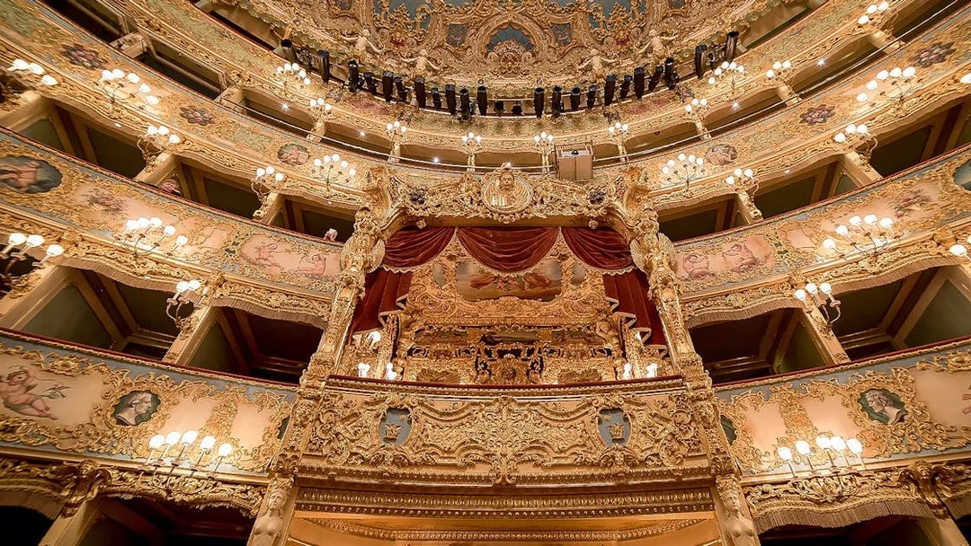 Ornate interior of Fenice Theater with gilded balconies and chandeliers.
