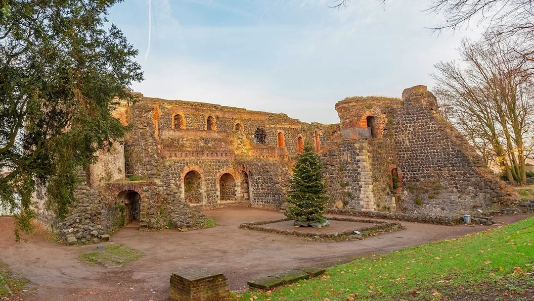 Ancient stone ruins with arches in Duesseldorf, Germany, surrounded by trees.