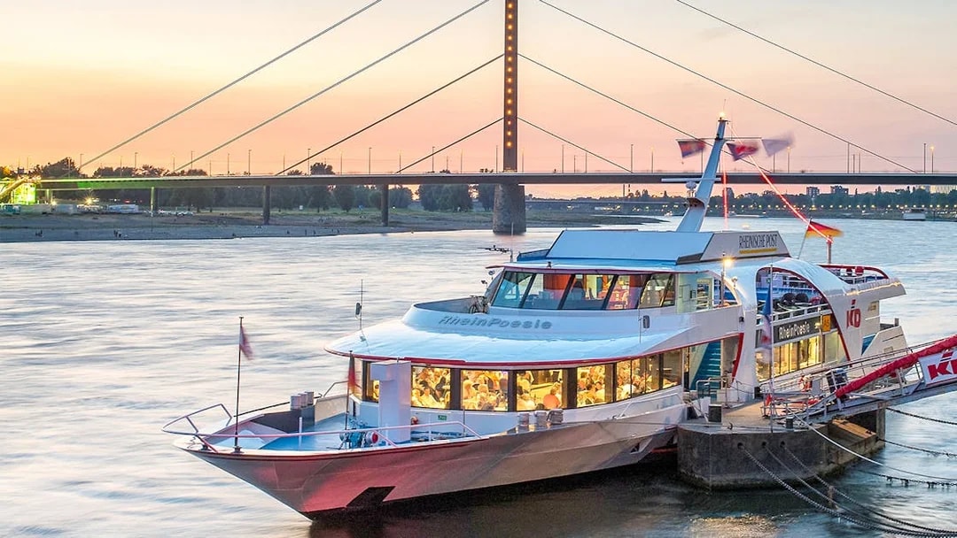 Cruise boat docked on the Rhine River at sunset in Düsseldorf.