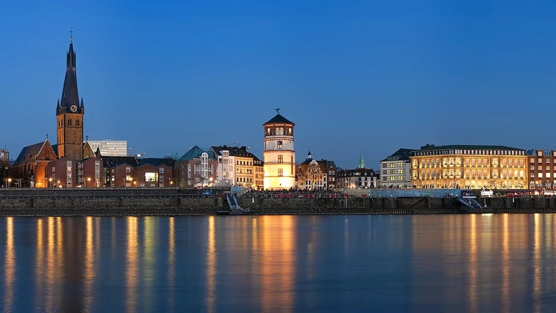 Duesseldorf skyline at dusk with illuminated buildings along the Rhine River during Panorama City Cruise.