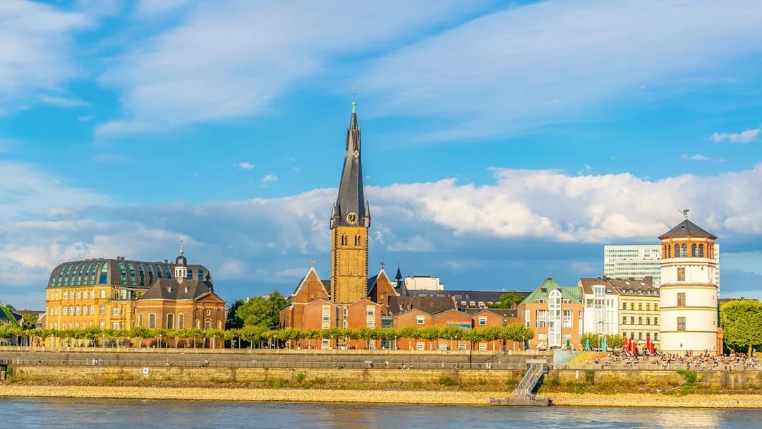 Riverside view of Düsseldorf with historic buildings and church spire on Panorama City Cruise.