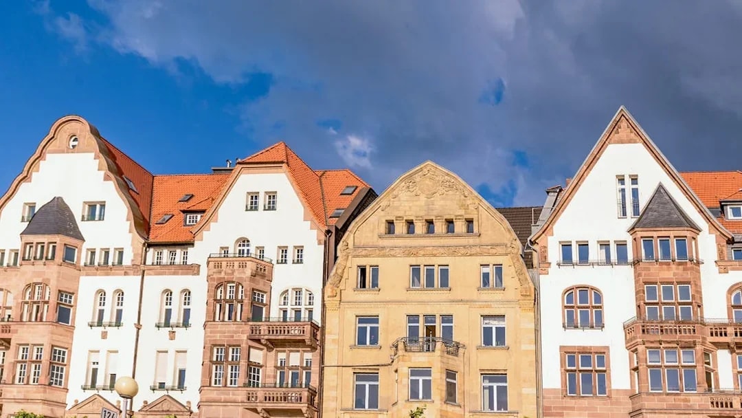 Historic buildings with red roofs in Düsseldorf under a cloudy sky.
