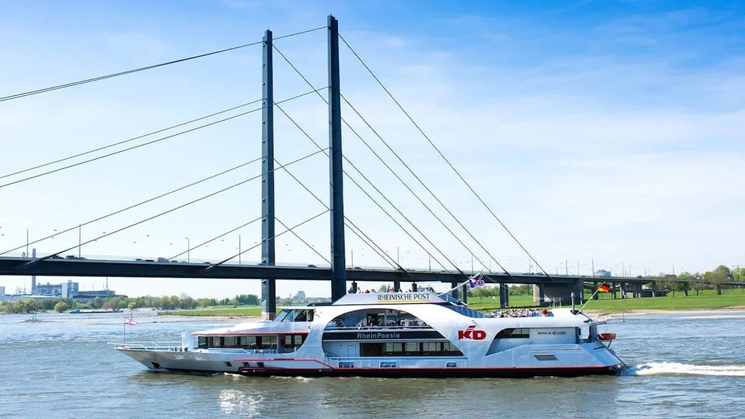 Cruise ship on the Rhine River passing under a bridge in Düsseldorf.
