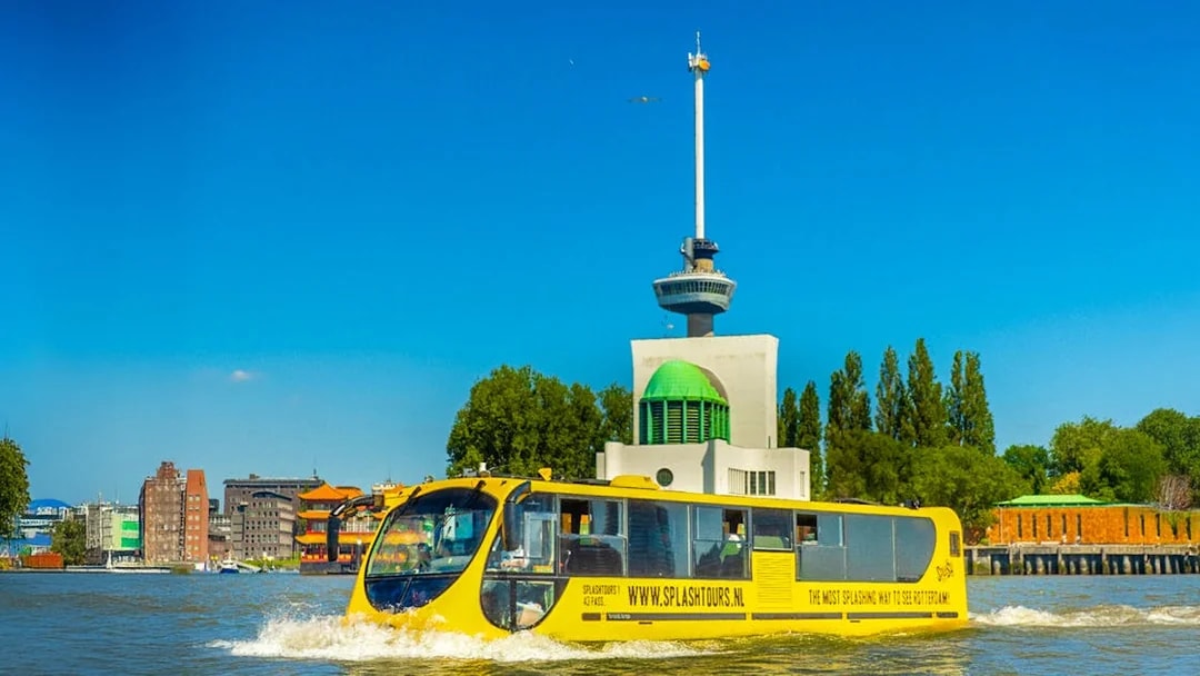 Yellow amphibious bus sailing near the Euromast in Rotterdam.