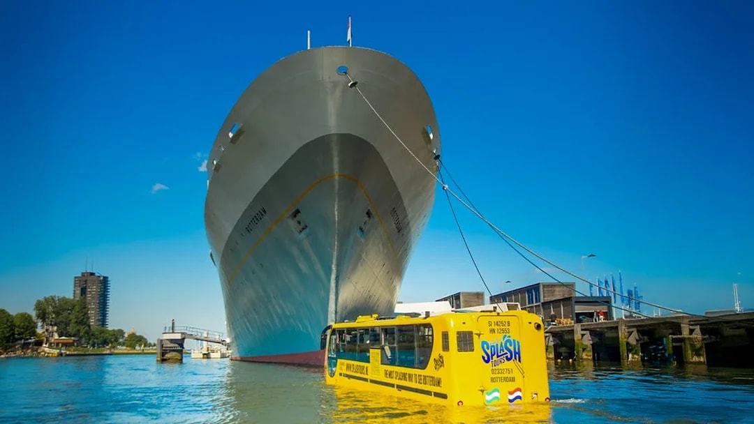 Amphibious bus on Rotterdam waterway near large ship during 1-hour sightseeing splash tour.