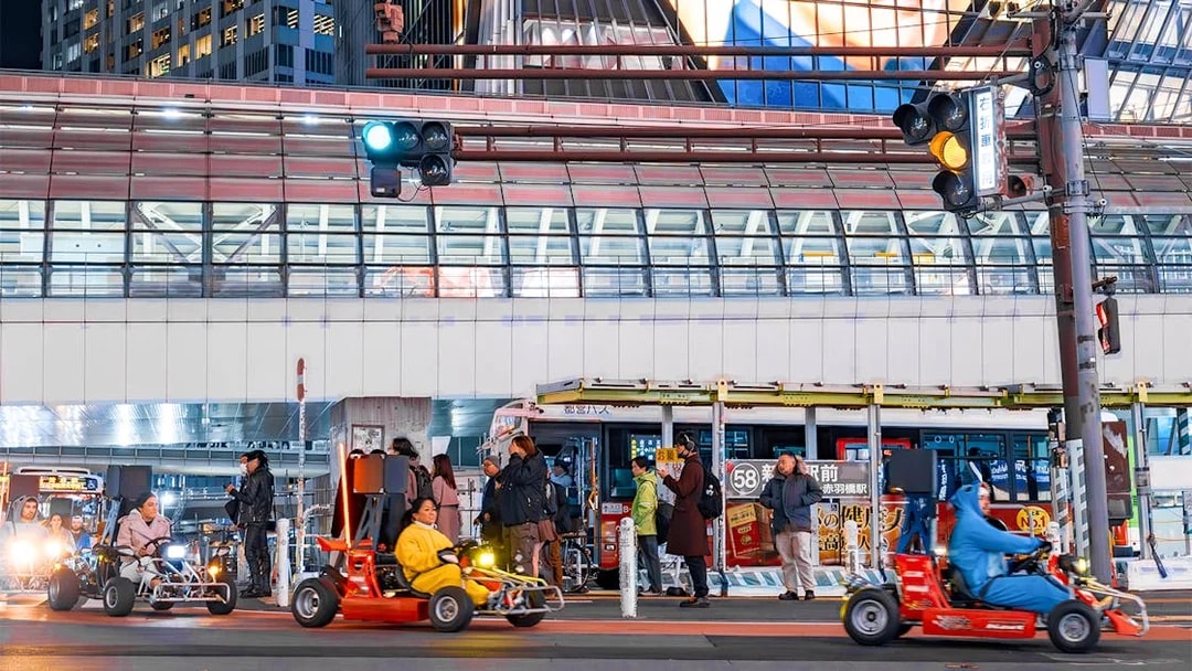 Nighttime go-karting on city streets with illuminated buildings in the background.