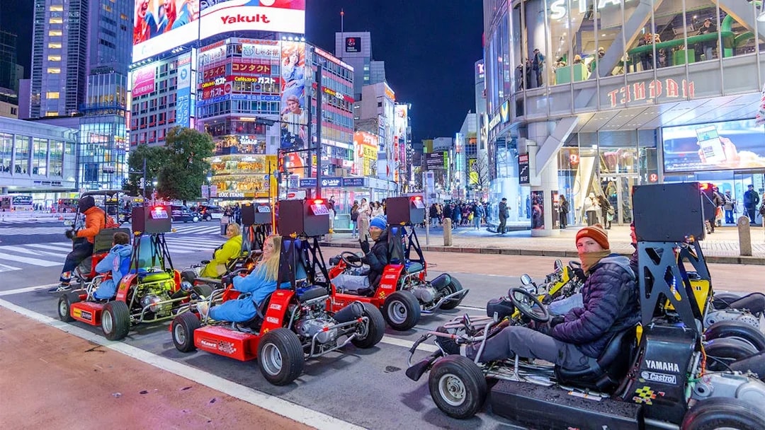 Go-karting at night in Shibuya, Tokyo, with illuminated cityscape and vibrant billboards.