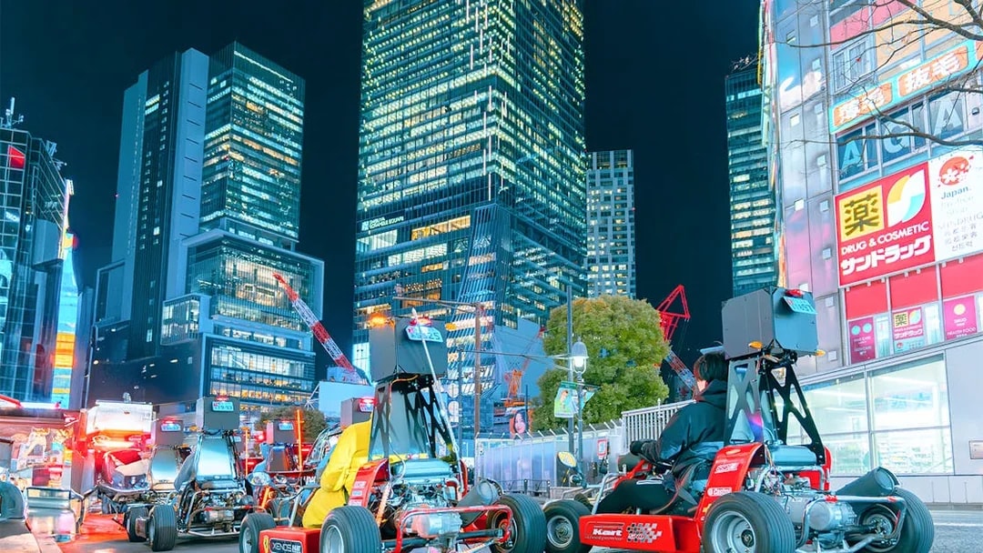 Go-karts driving through illuminated city streets at night.