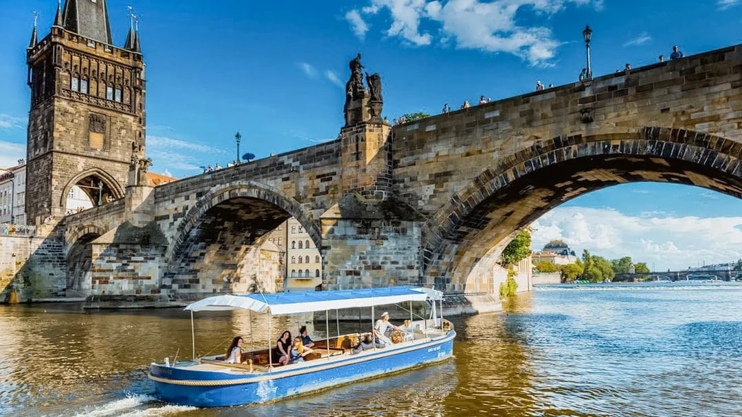 Sightseeing cruise boat passing under Charles Bridge in Prague's Devils Channel.