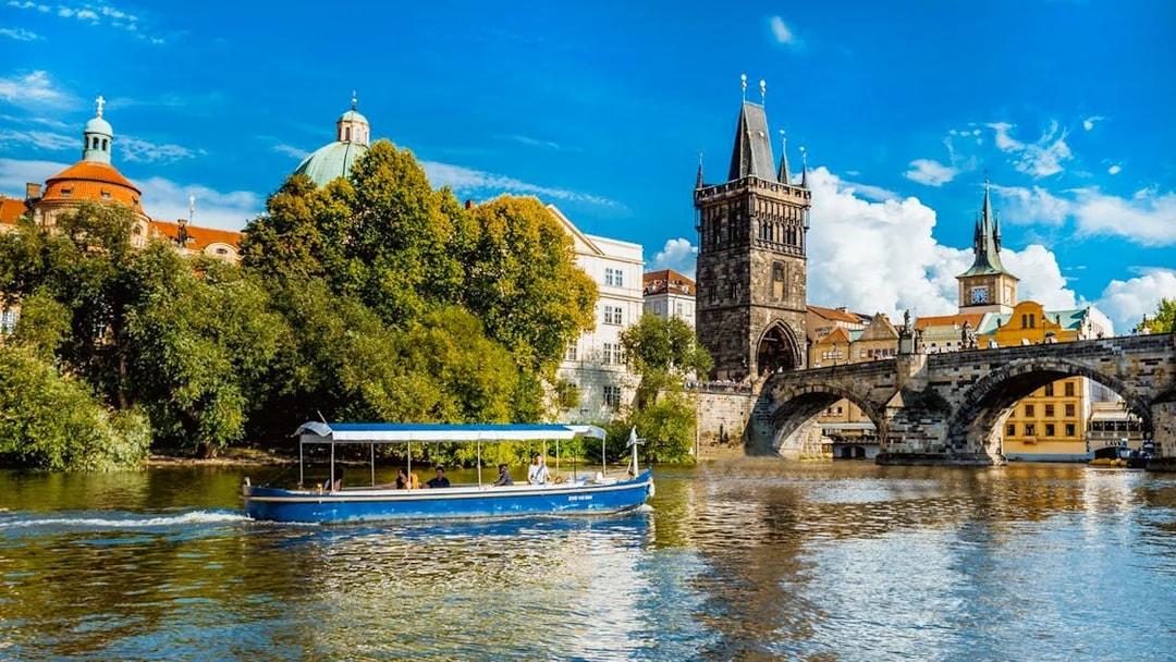 Sightseeing cruise boat on Vltava River near Charles Bridge, Prague.
