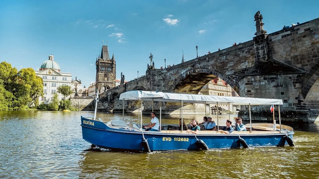 Sightseeing cruise boat on Vltava River near Charles Bridge, Prague.