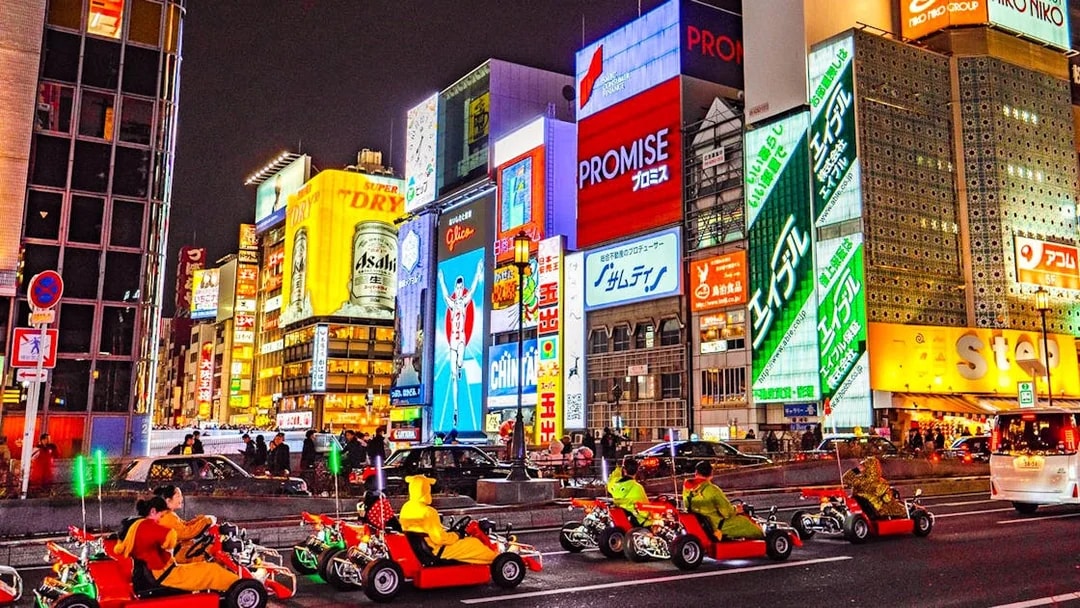 Go-karts driving through illuminated streets of Osaka during Akiba Kart experience.