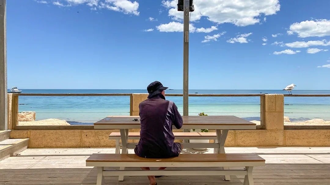 Person sitting at a picnic table overlooking the ocean on Australia's Pinnacles tour.