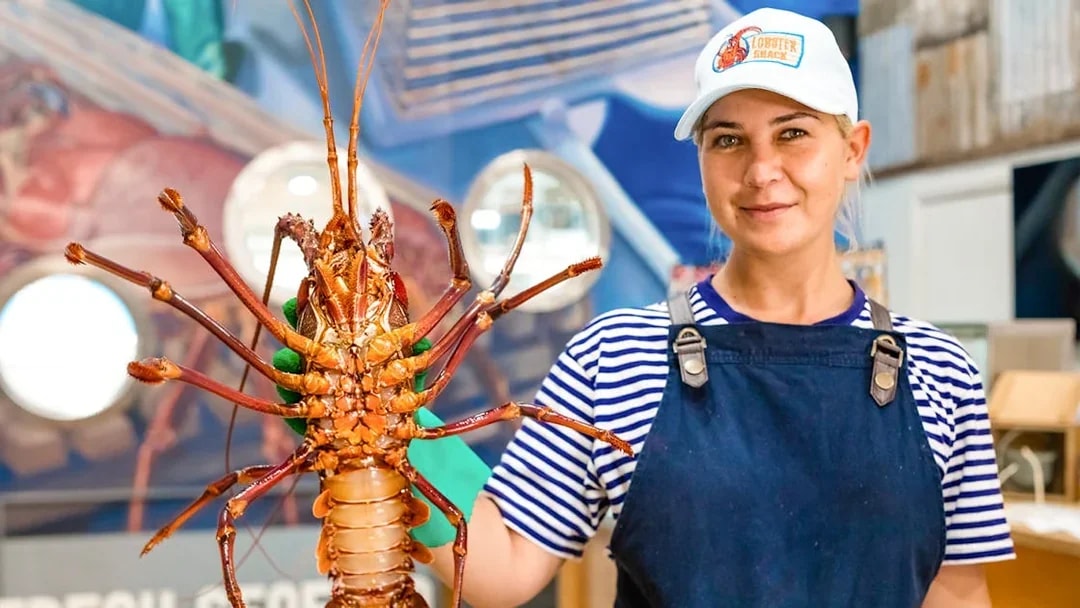 Person holding a large lobster at a seafood restaurant in Australia.