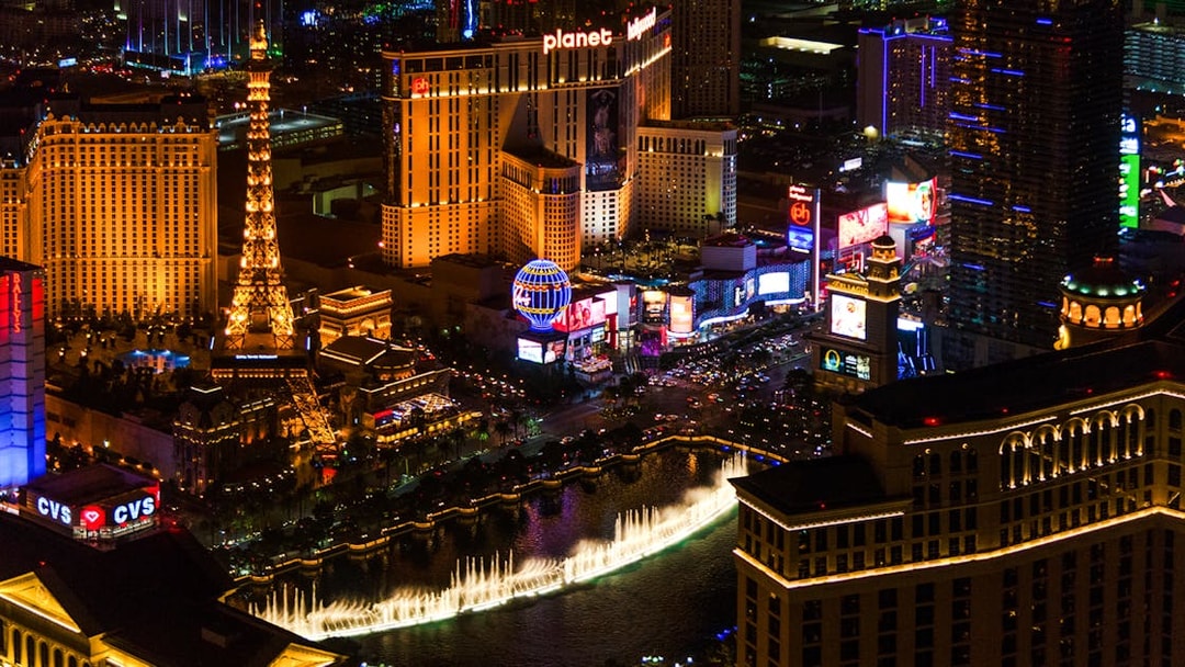Aerial view of the illuminated Las Vegas Strip at night featuring the Eiffel Tower replica and Bellagio fountains.