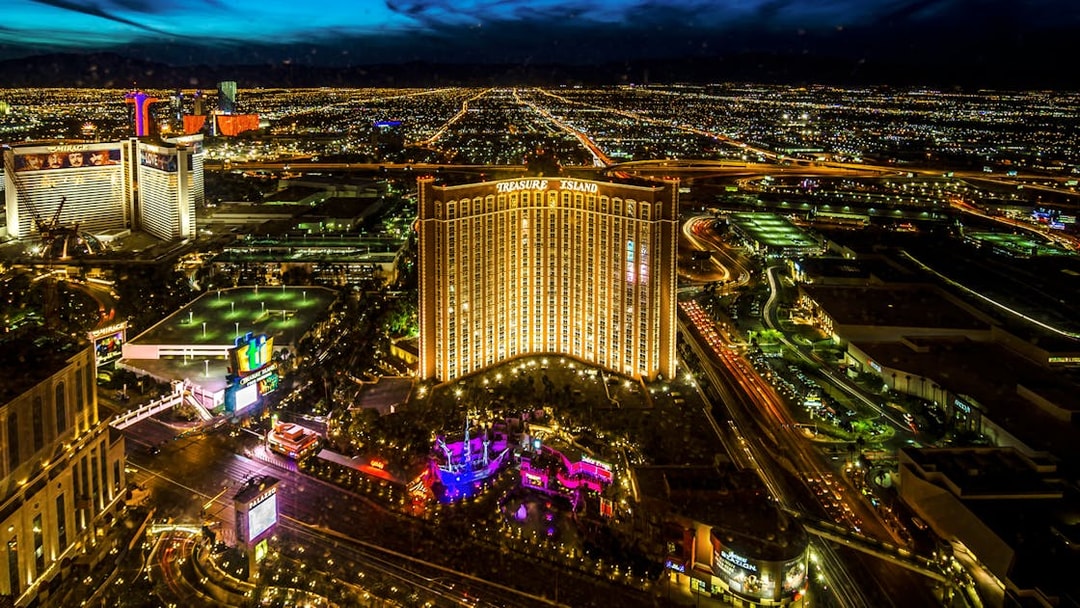 Aerial view of Las Vegas Strip at night with Treasure Island Hotel and Casino illuminated.