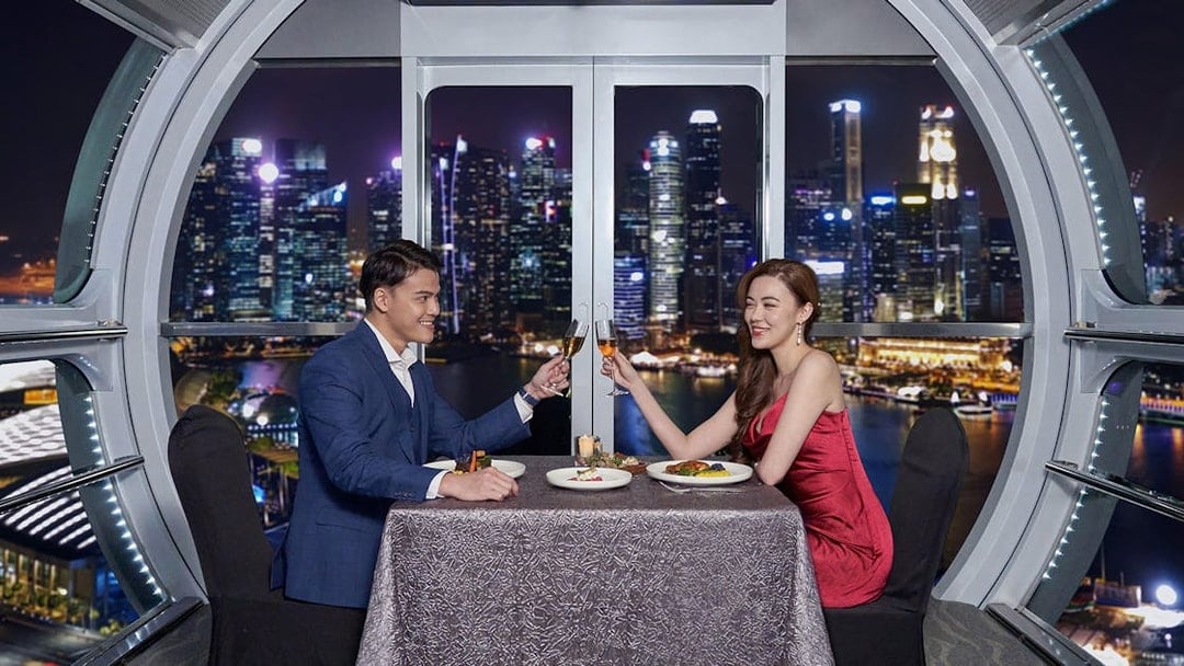 Couple dining at Singapore Flyer with city skyline view.