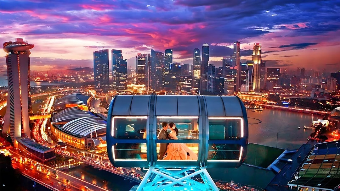 Couple in a cabin on the Singapore Flyer with city skyline at sunset.